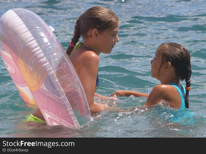 Two girls of teenager bath in a sea on a rubber circle. Two girls of teenager bath in a sea on a rubber circle