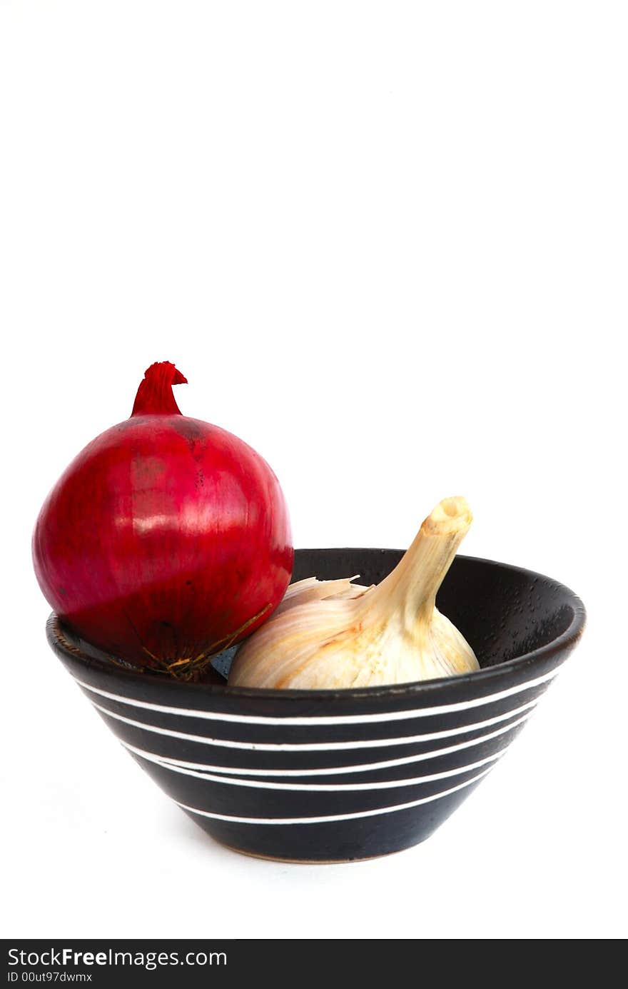 Red onion and garlic in a black bowl with white pattern