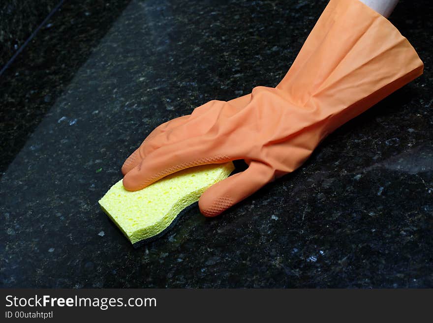 A person cleaning the Kitchen Counter with a glove. A person cleaning the Kitchen Counter with a glove