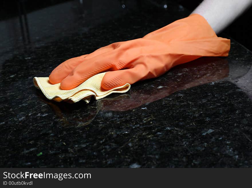 A person cleaning the Kitchen Counter with a glove. A person cleaning the Kitchen Counter with a glove