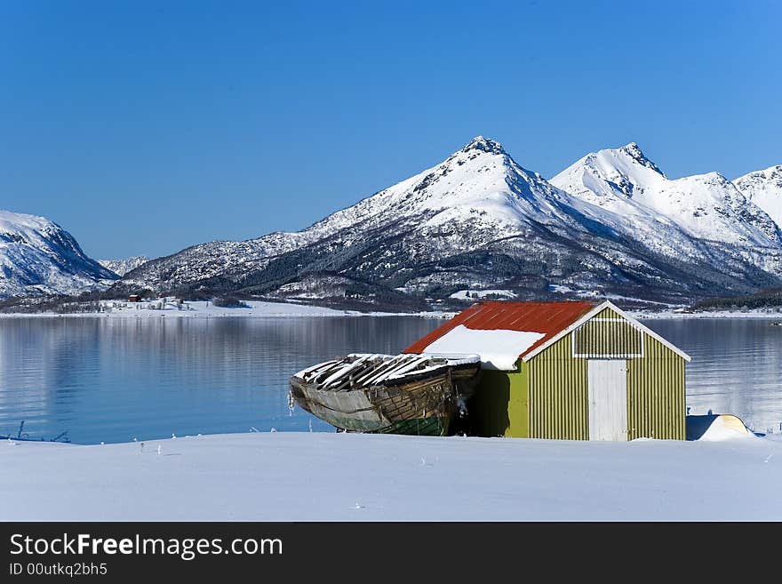 Boat house with old boat and mountains in the background