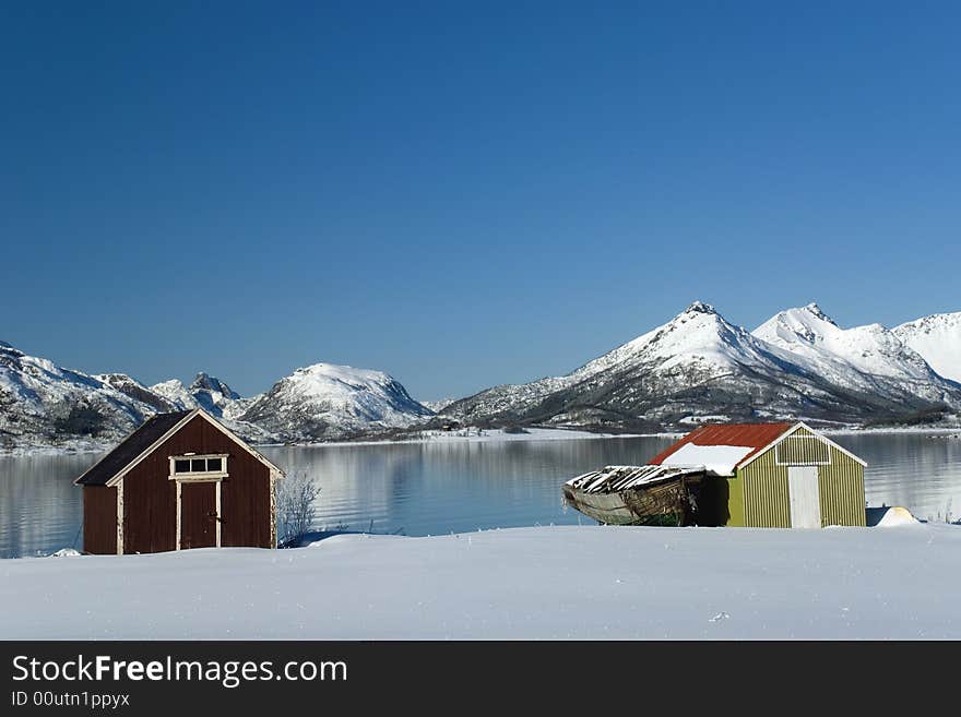 Boat houses with old boat and mountains in the background. Boat houses with old boat and mountains in the background