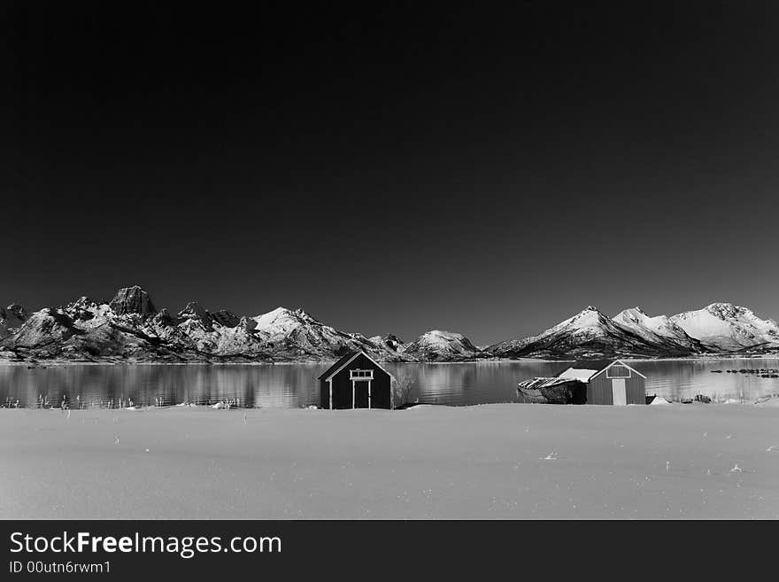 Boat houses with old boat and mountains in the background black and white. Boat houses with old boat and mountains in the background black and white