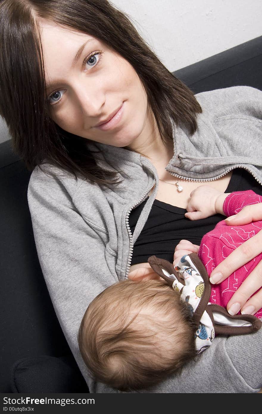 Young mother on a sofa with their baby girl. Young mother on a sofa with their baby girl