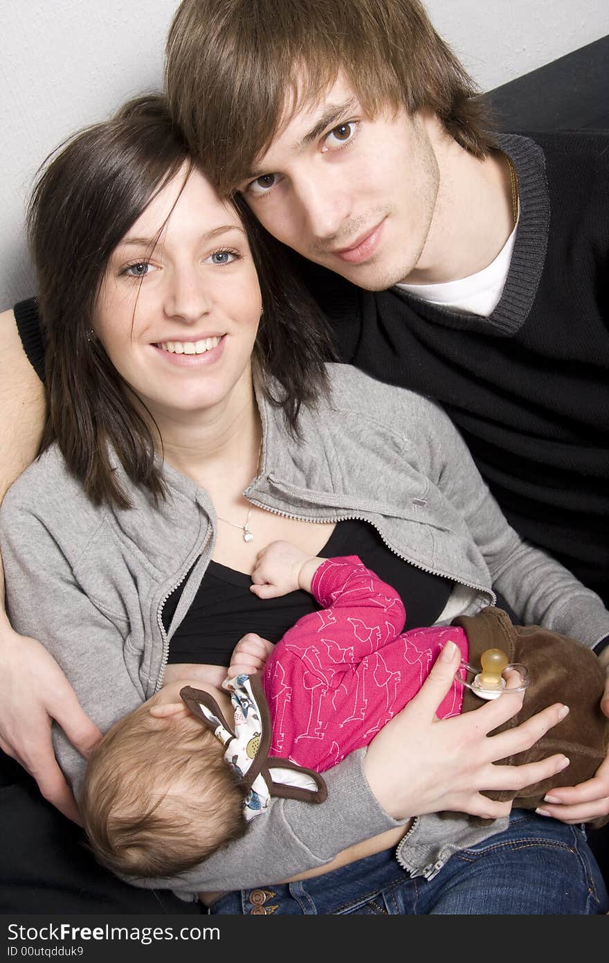 Young parents on a sofa with their baby girl