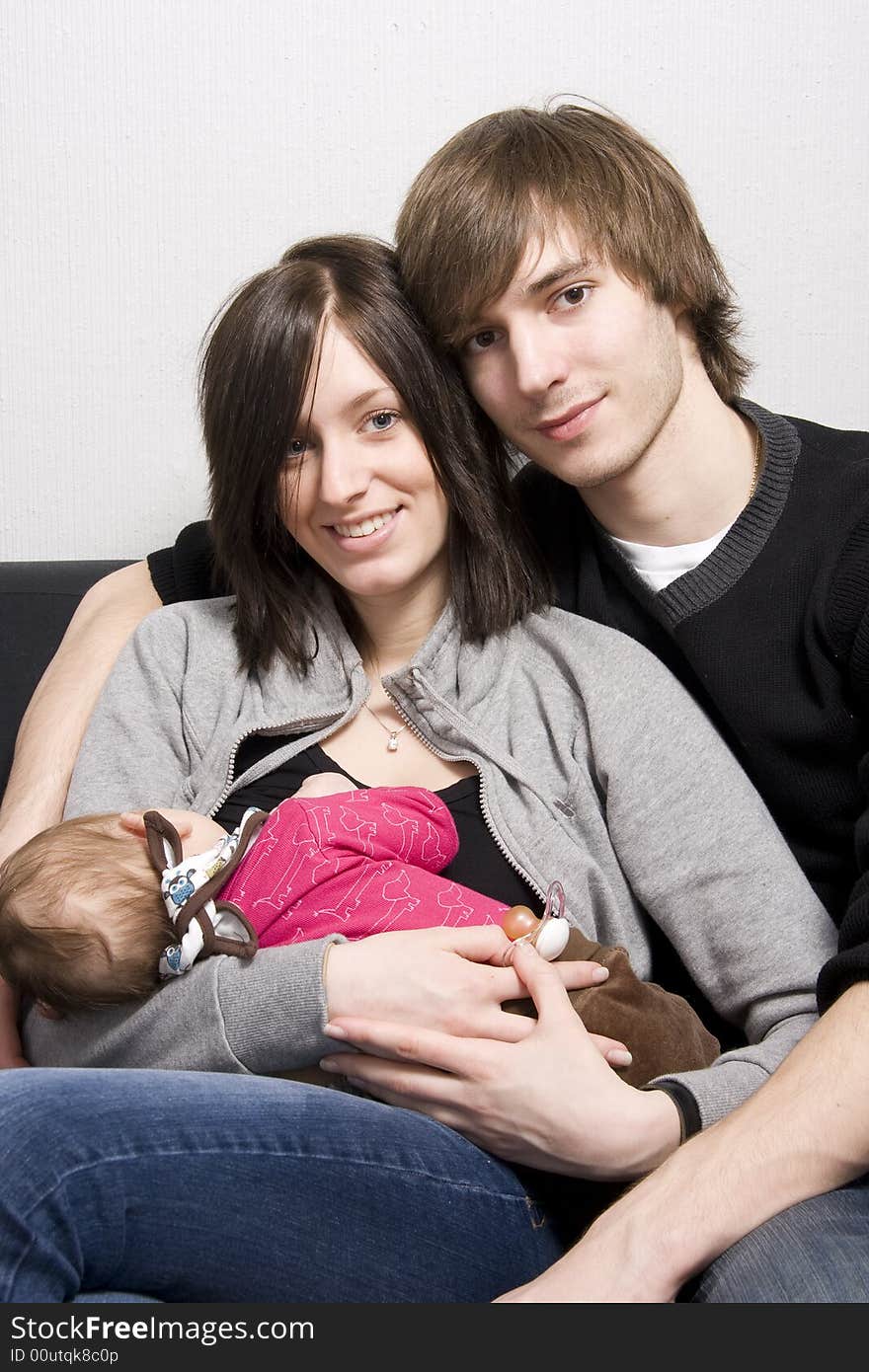 Young parents on a sofa with their baby girl