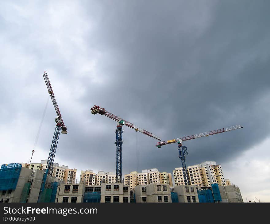 Cranes at rest at a construction site as a tropical convectional storm set to break. Cranes at rest at a construction site as a tropical convectional storm set to break