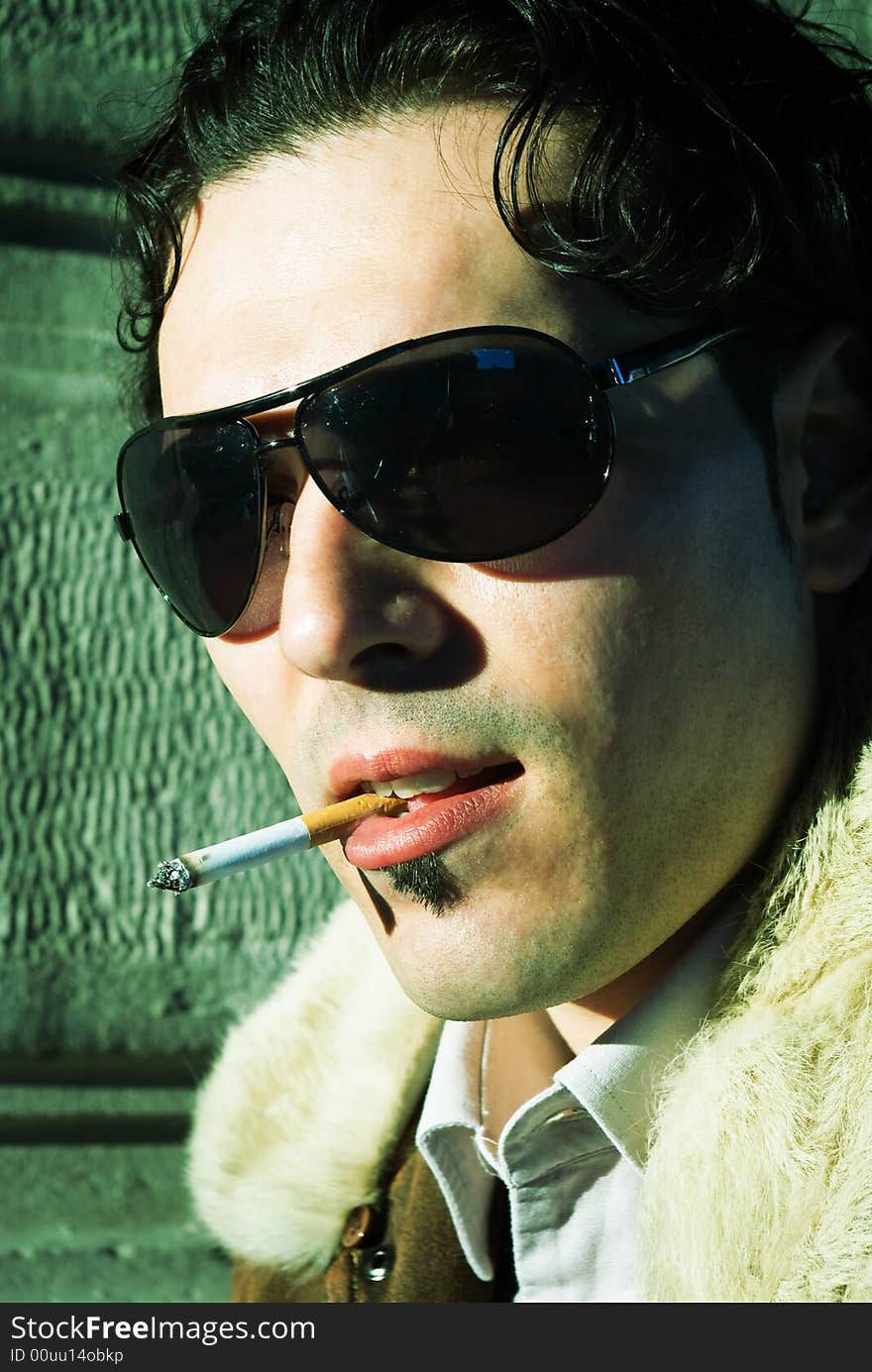 Sexy young man with sunglasses smoking a cigarette, 70's style, vintage style. Sexy young man with sunglasses smoking a cigarette, 70's style, vintage style