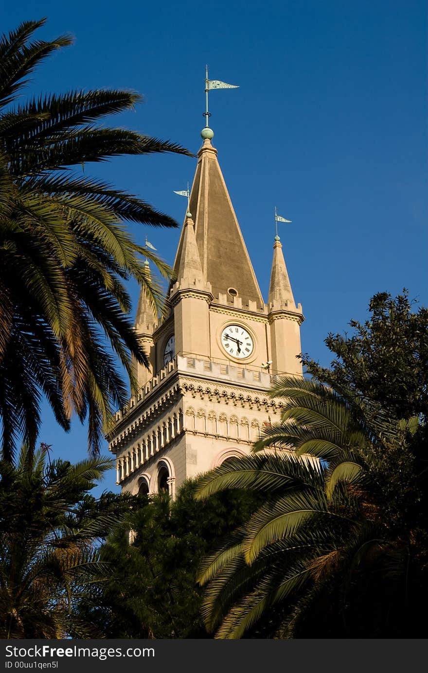 Clock tower and palm trees defined against the blue sky