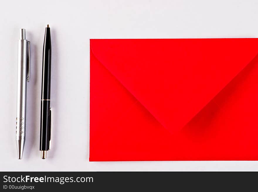 Two pens and a red envelope on a white background