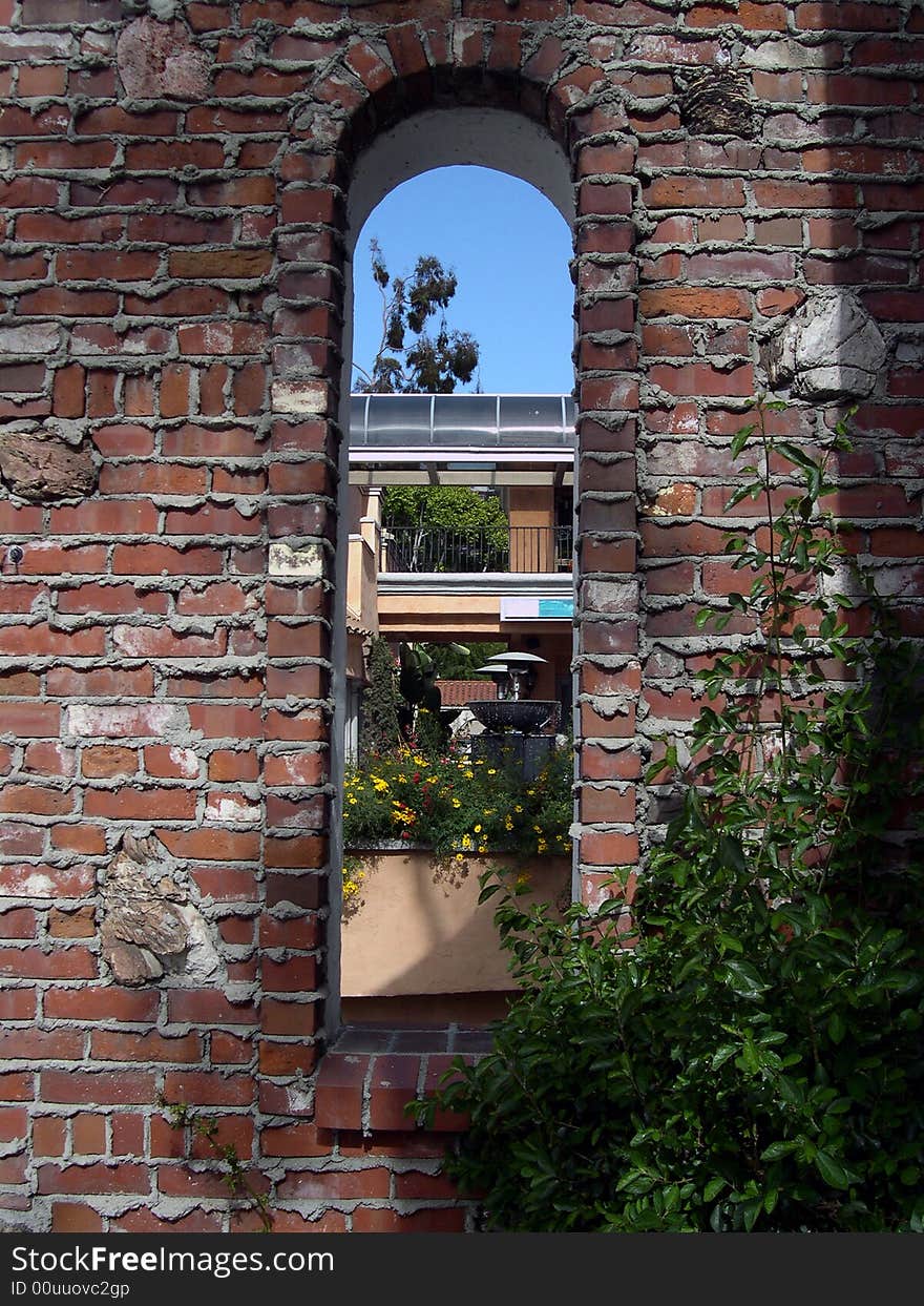 Window in a brick wall, with fountain in the background. Window in a brick wall, with fountain in the background.