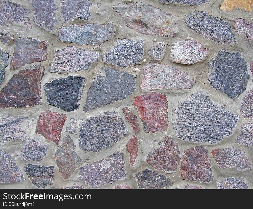 Wall from the varicoloured granite of clamped by cement solution. Wall from the varicoloured granite of clamped by cement solution