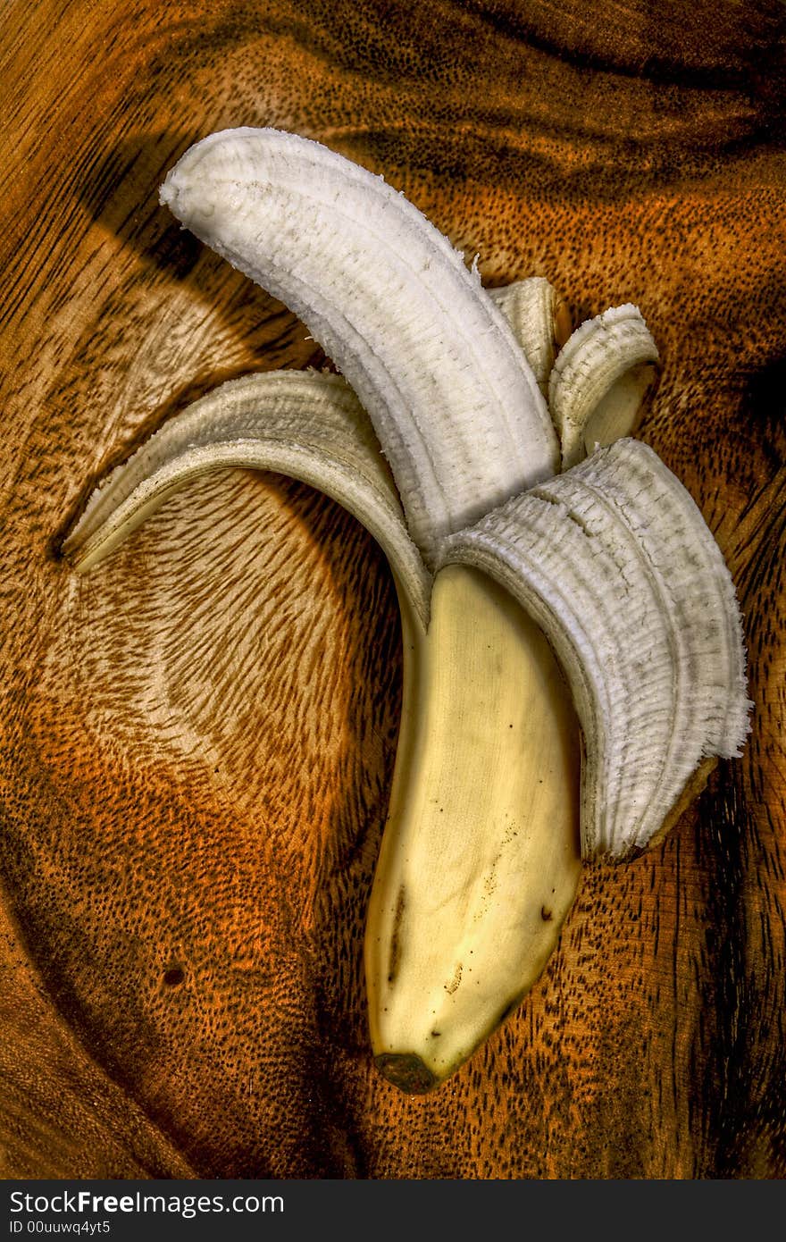 Peeled banana sitting in a wooden bowl.