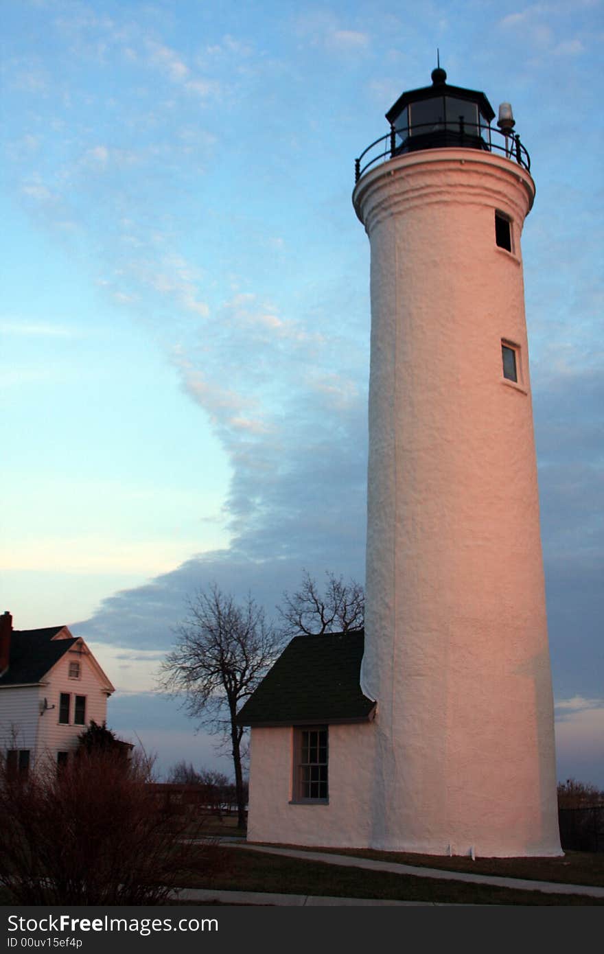 A distant sun set cast a golden glow on the side of this historic light house.  It has guarded the point where Lake Ontario turns into the St. Lawrence River. A distant sun set cast a golden glow on the side of this historic light house.  It has guarded the point where Lake Ontario turns into the St. Lawrence River.