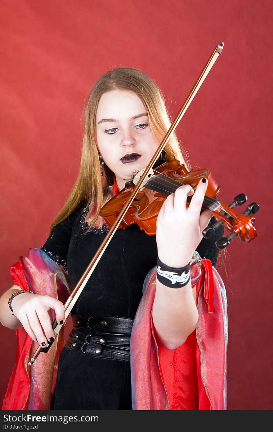 The young woman with gothic cosmetics plays on a violin. The young woman with gothic cosmetics plays on a violin.