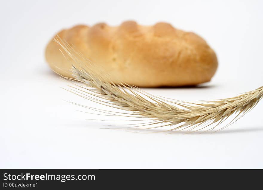 Close-up at wheat ear on background with white bread stick. Close-up at wheat ear on background with white bread stick