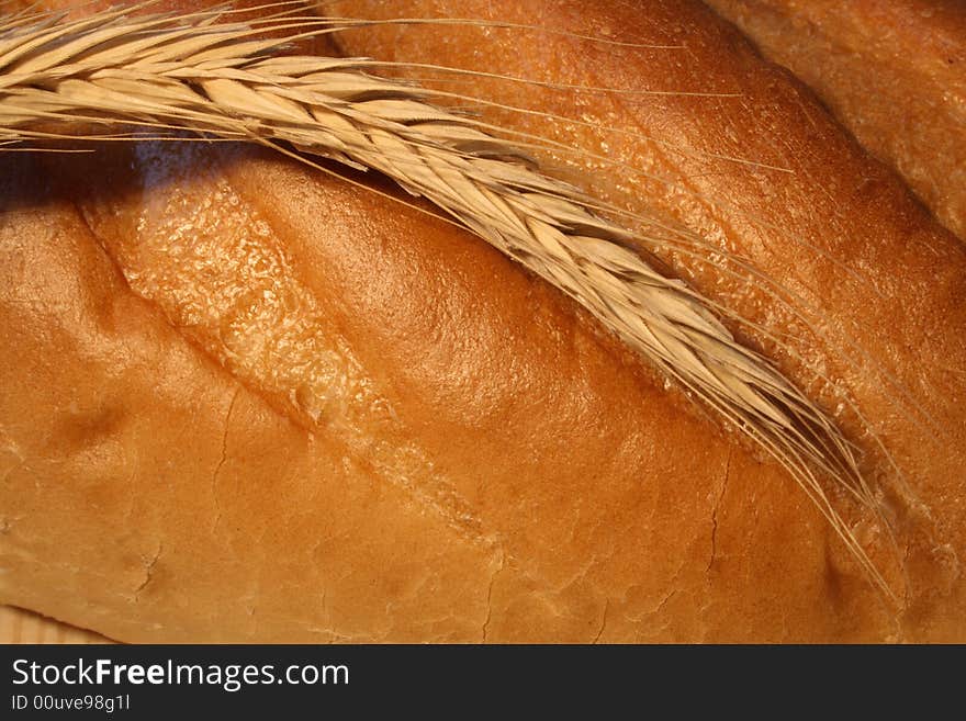 Close-up at wheat ear lying on fresh-baked white bread. Close-up at wheat ear lying on fresh-baked white bread