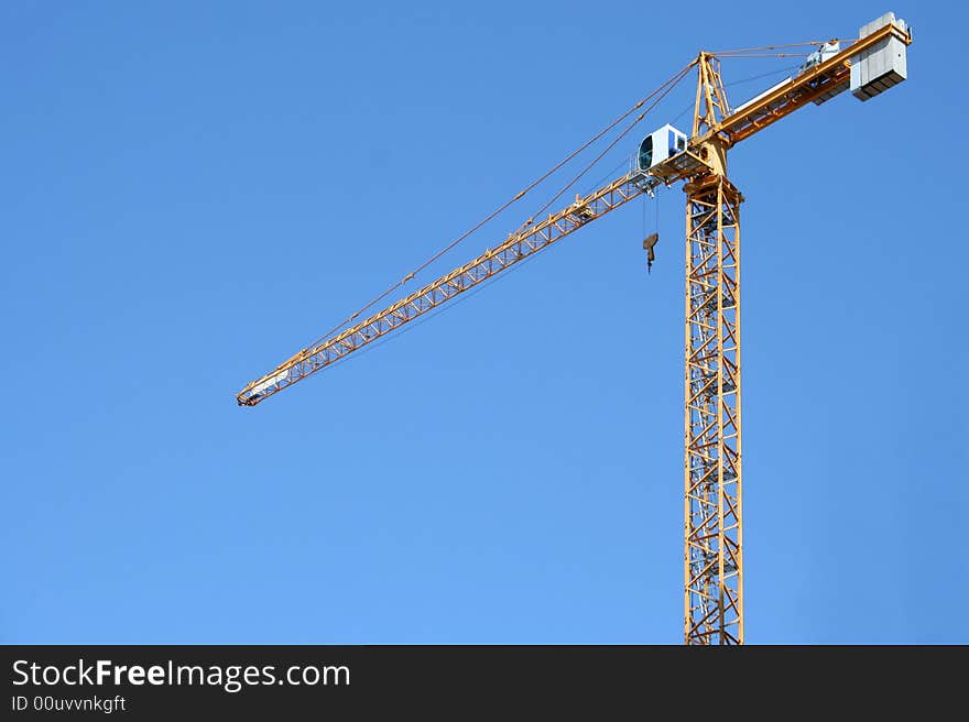 The building crane on a background of the blue sky