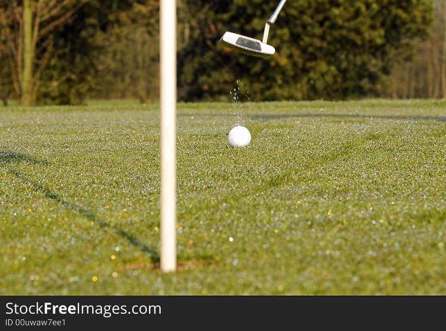 Golf ball on green with flag and putter. Golf ball on green with flag and putter