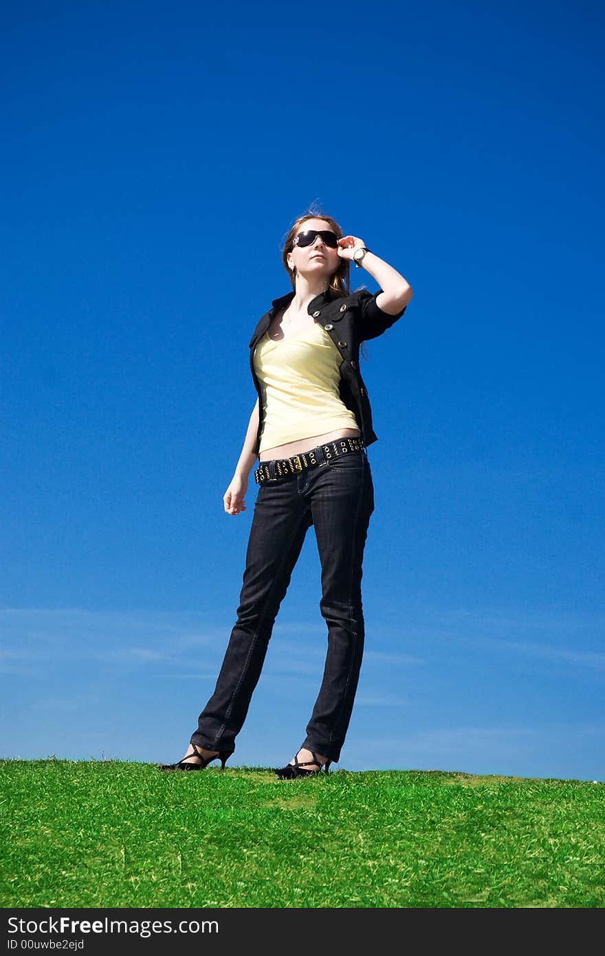 The young attractive girl on a background of the blue sky