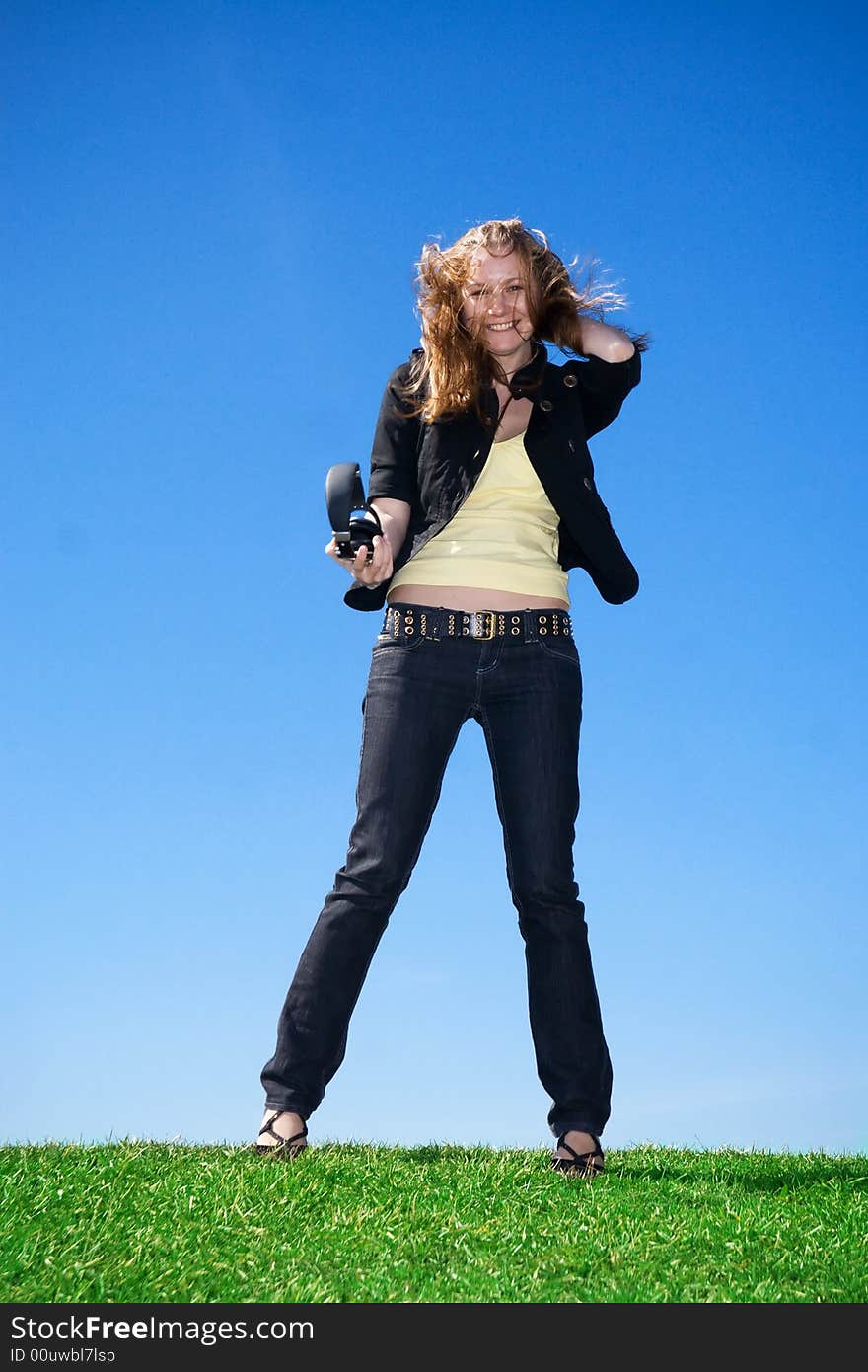 The young attractive girl with headphones on a background of the blue sky