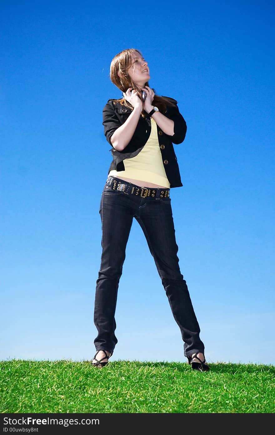 The young attractive girl with headphones on a background of the blue sky