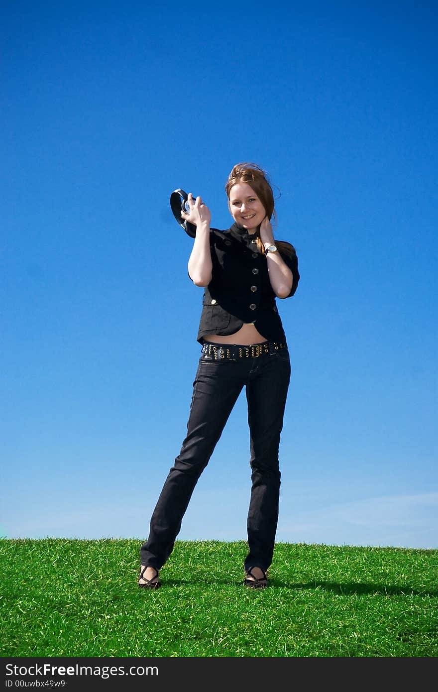 The young attractive girl with headphones on a background of the blue sky