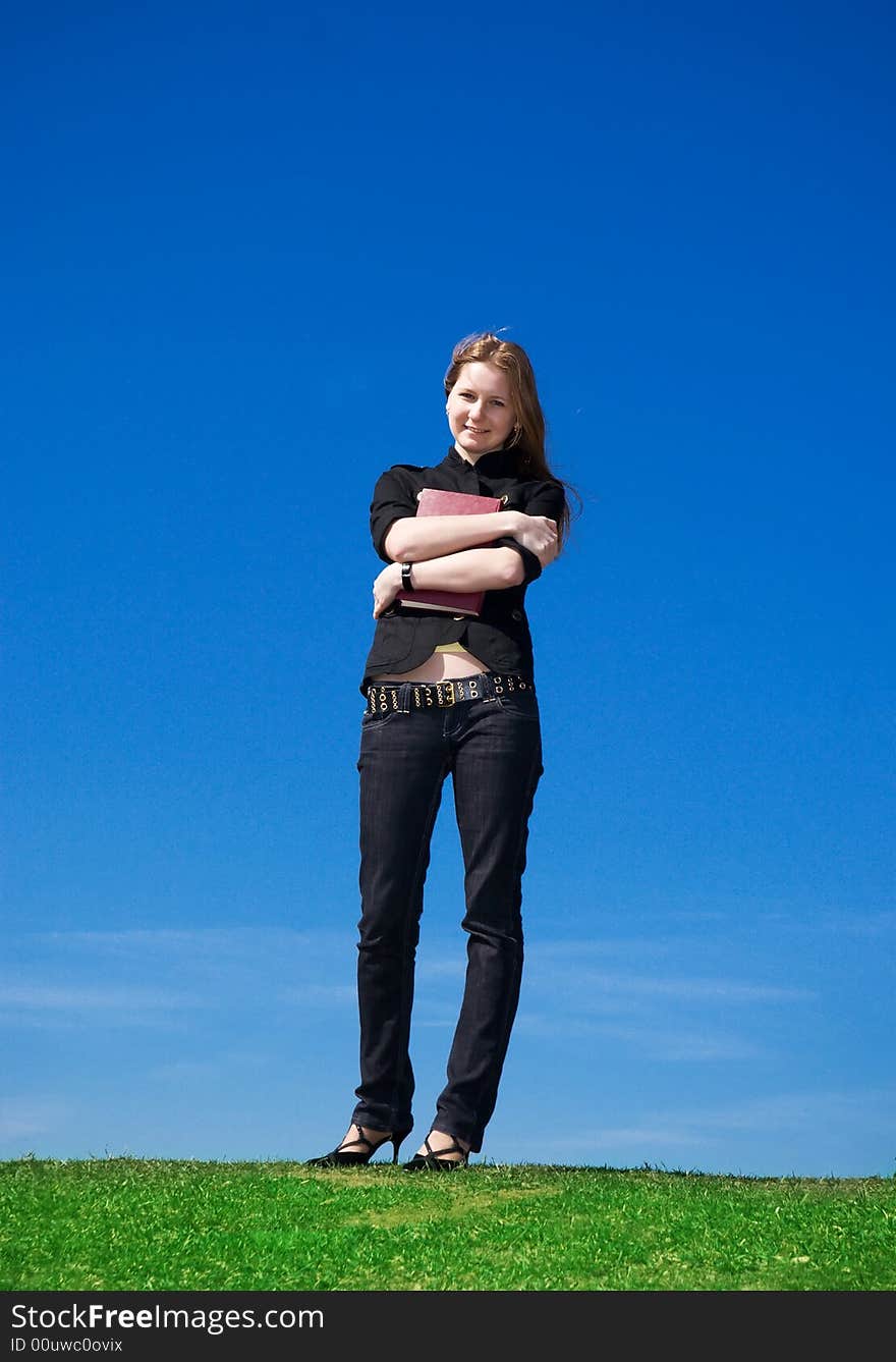 The young attractive student with the book on a background of the blue sky