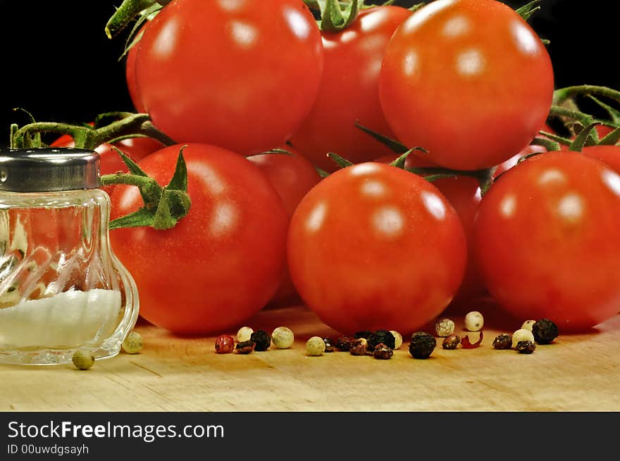 A bunch of tomatoes on wood with salt and pepper. A bunch of tomatoes on wood with salt and pepper