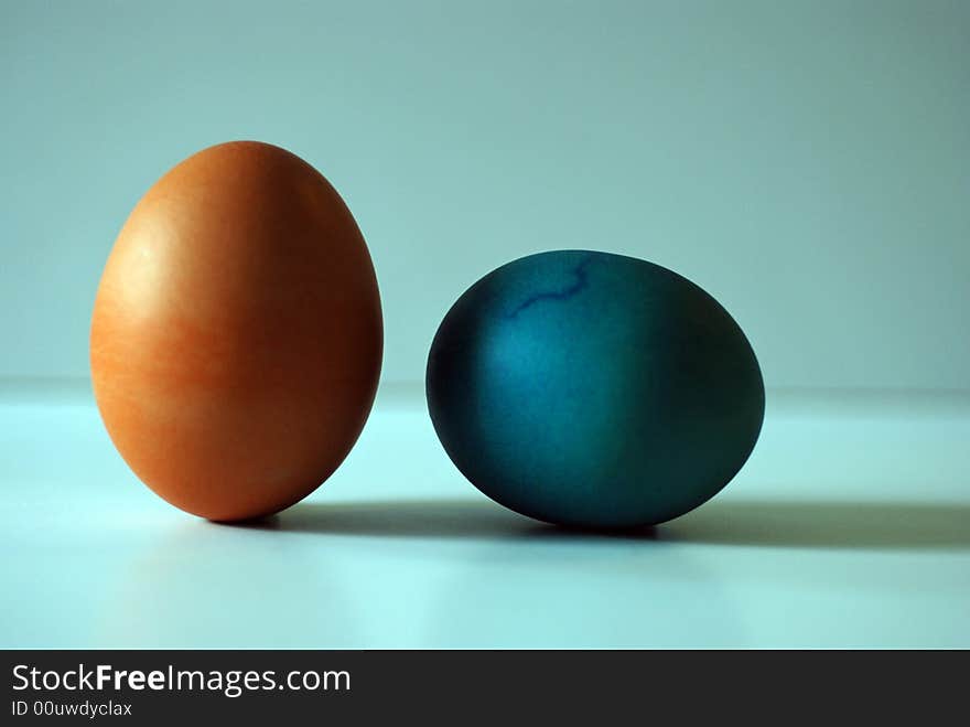 Two colored hard boiled eggs against a blue background. Two colored hard boiled eggs against a blue background.