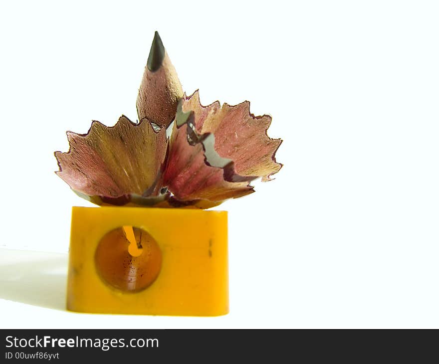 Pencil with sharpener, shavings on white background.