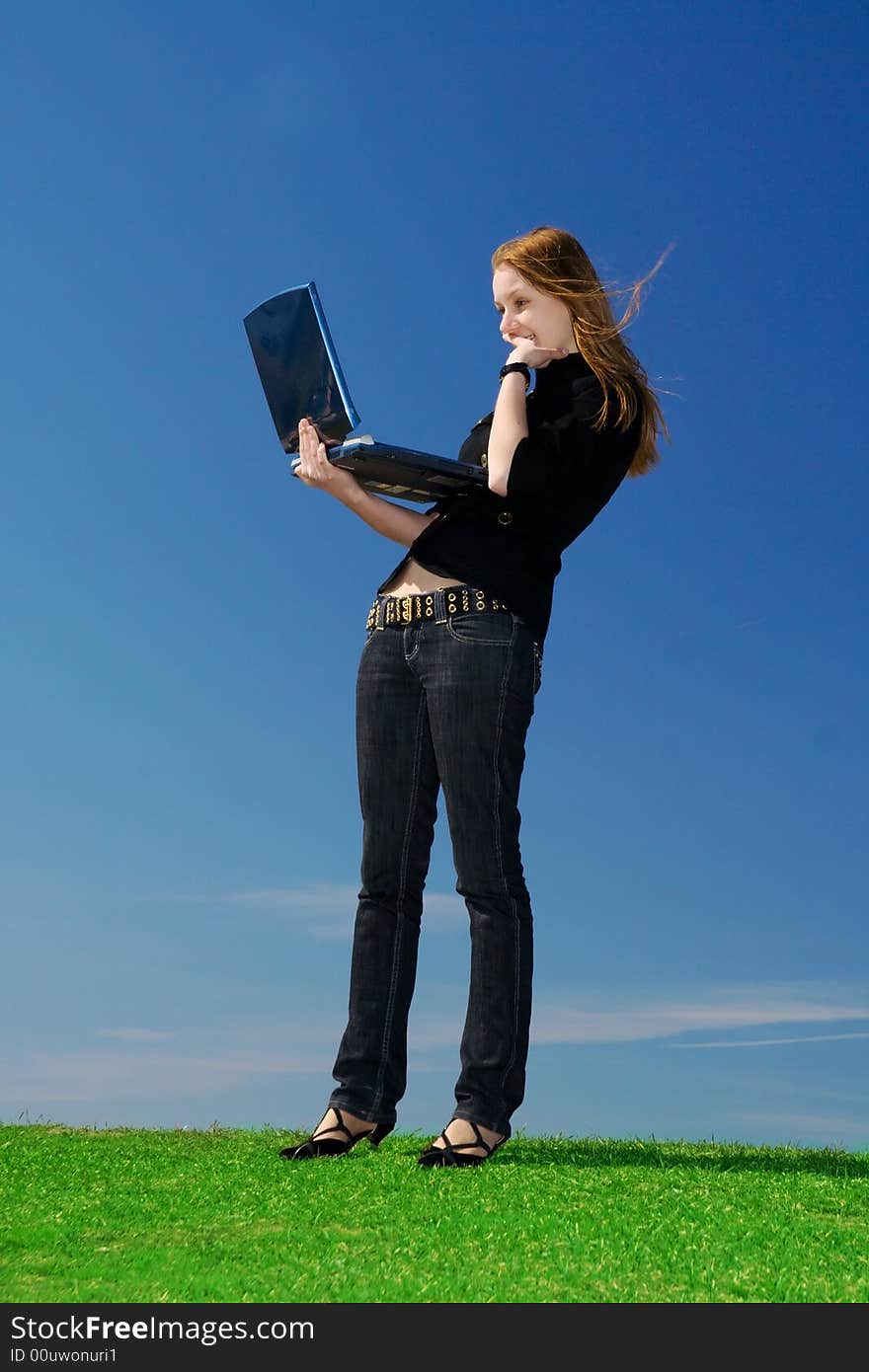 The young attractive girl with the laptop on a background of the blue sky