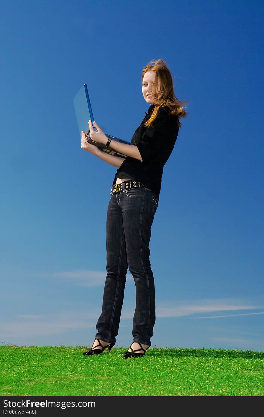 The young attractive girl with the laptop on a background of the blue sky