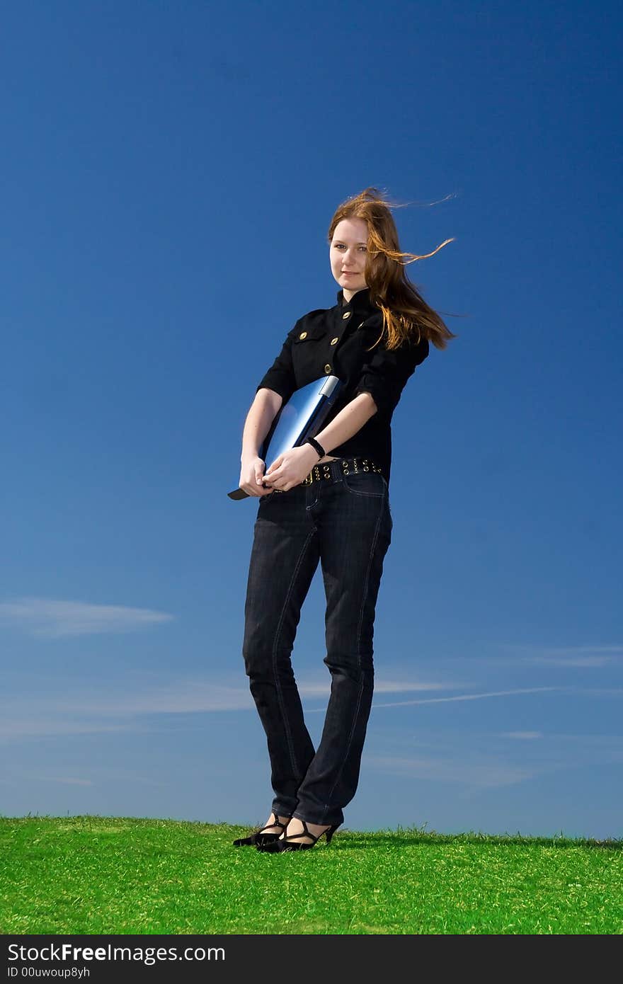 The young attractive girl with the laptop on a background of the blue sky