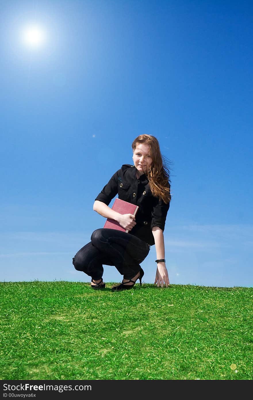 The young attractive student with the book on a background of the blue sky