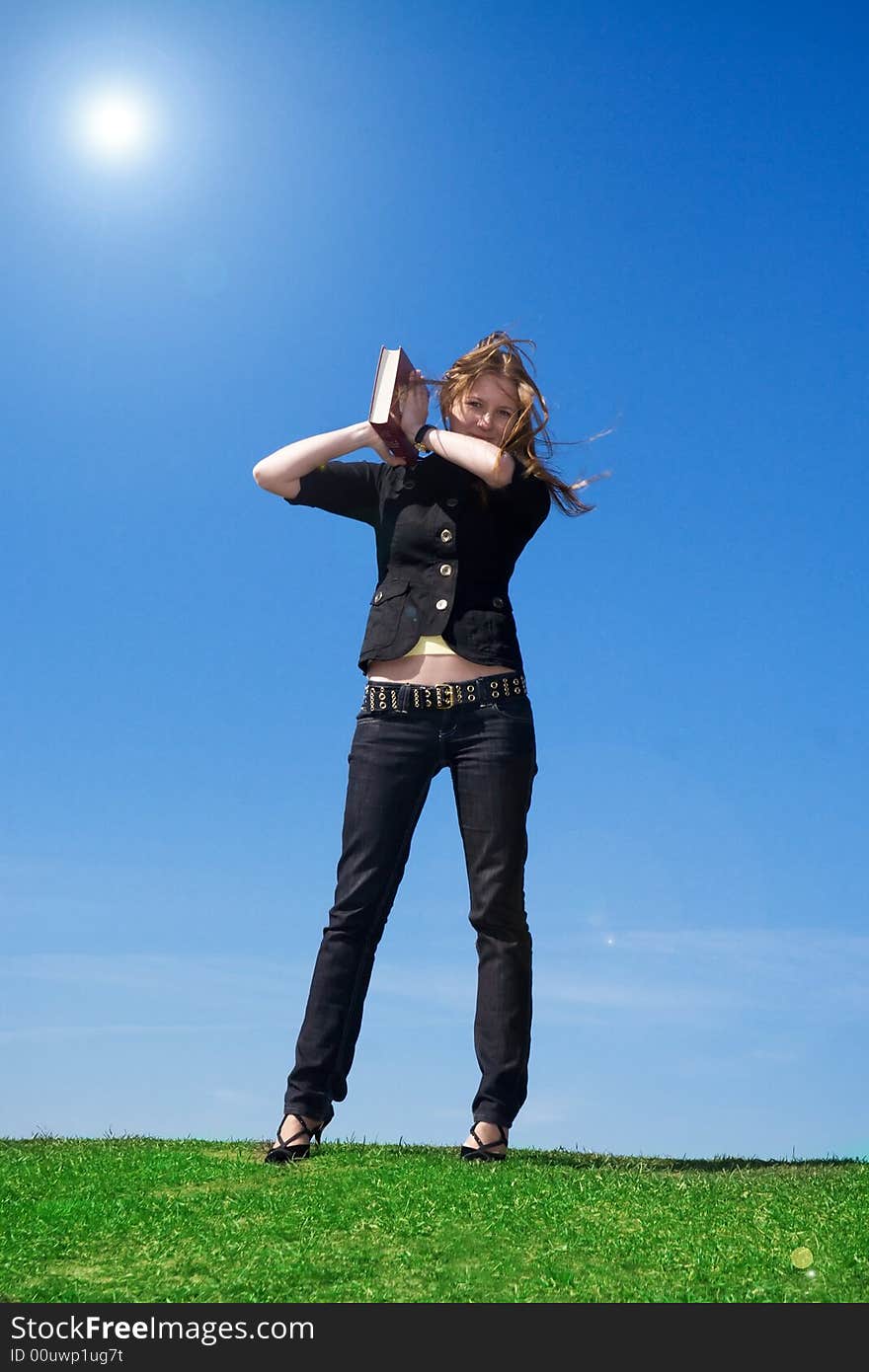 The young attractive student with the book on a background of the blue sky