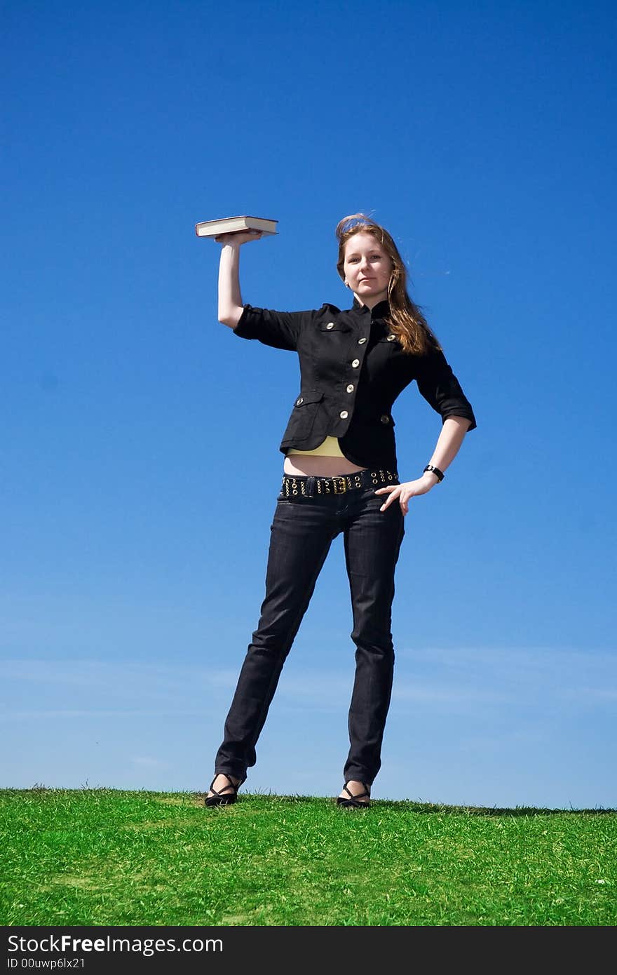 The young attractive student with the book on a background of the blue sky