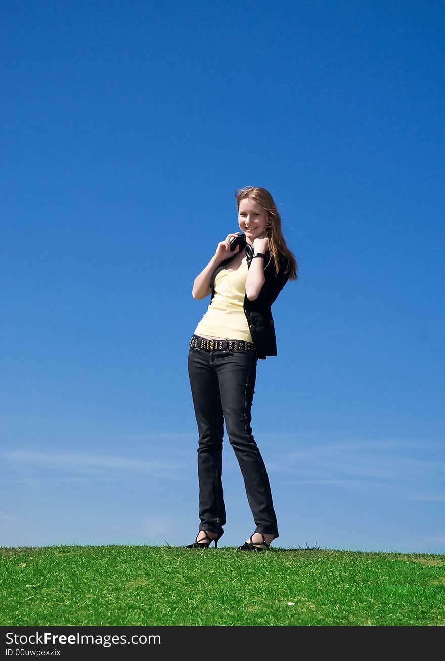 The young attractive girl with headphones on a background of the blue sky