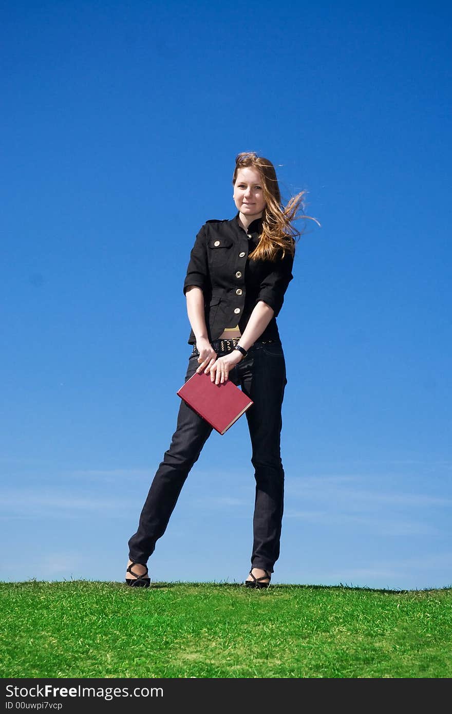 The young attractive student with the book on a background of the blue sky