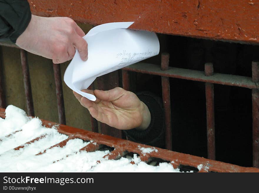 A sheet of paper passed on from a grilled basement window partially covered with snow. A sheet of paper passed on from a grilled basement window partially covered with snow.