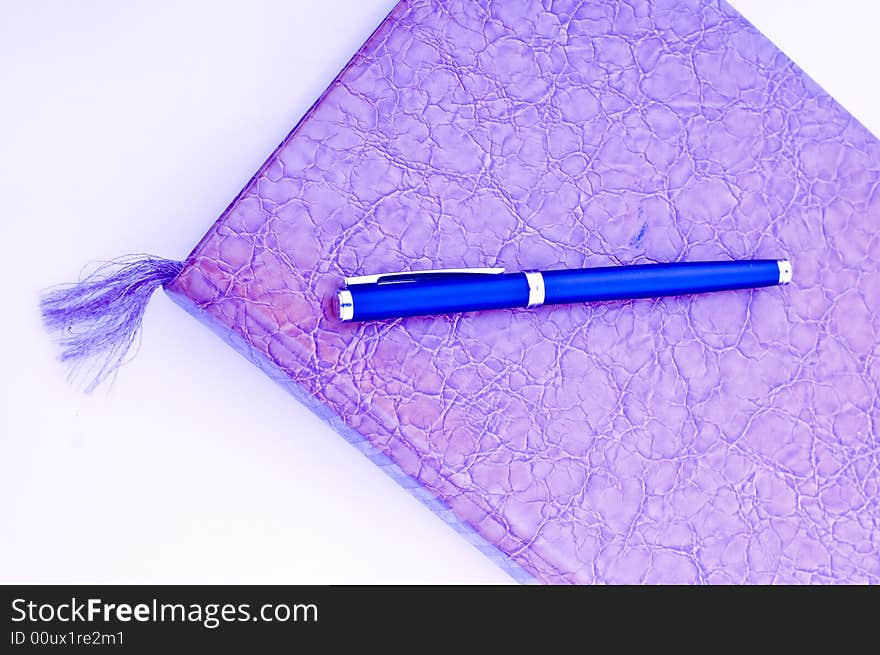 A high key photo of a book or notebook with a pen as the bookmark. A high key photo of a book or notebook with a pen as the bookmark.