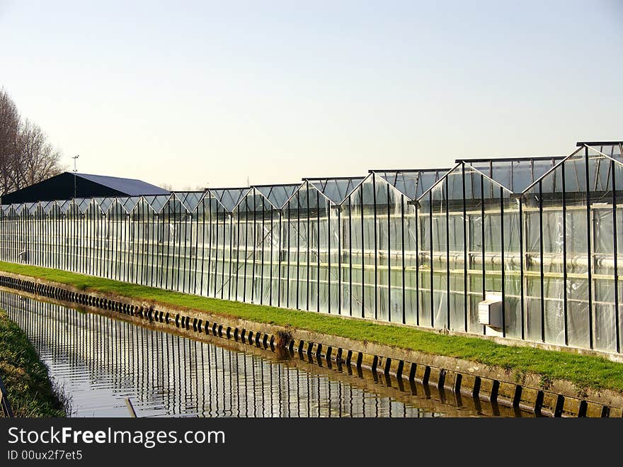 A greenhouse along a canal and reflections in the water