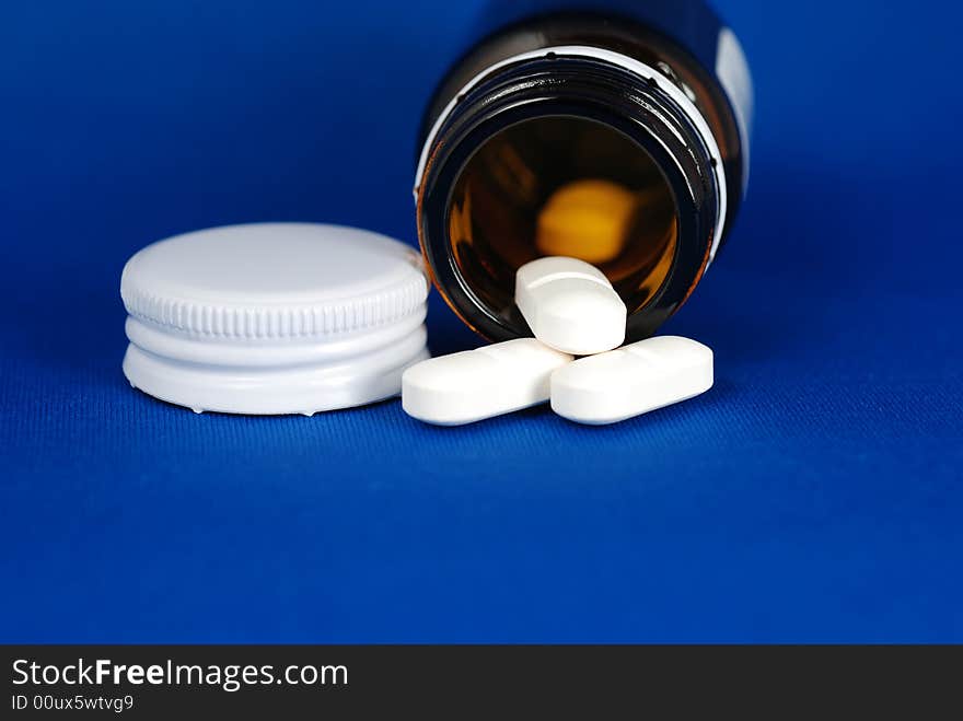 An open bottle of medicine with lid on blue background