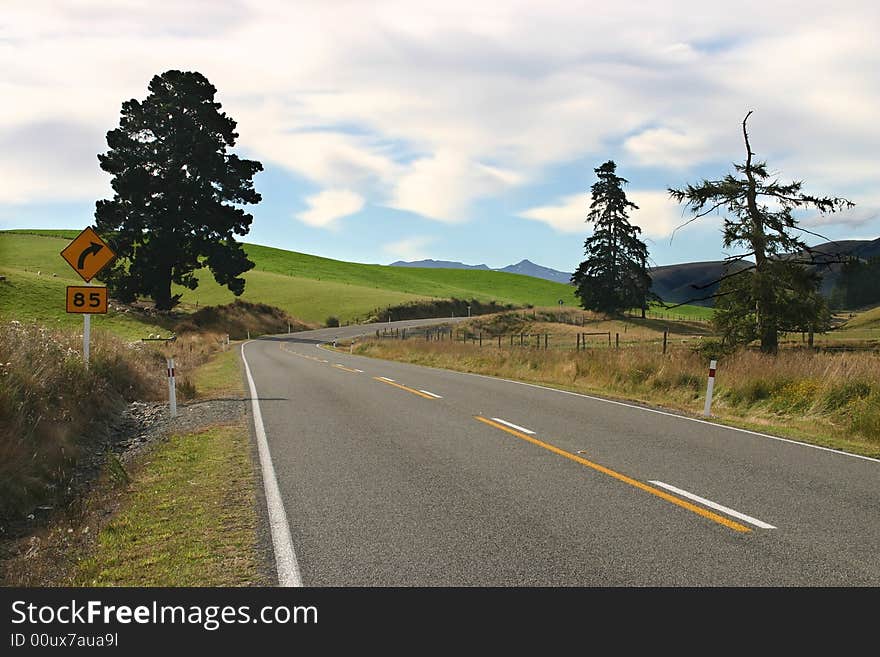 Winding road beside green rolling landscape. South Island. New Zealand