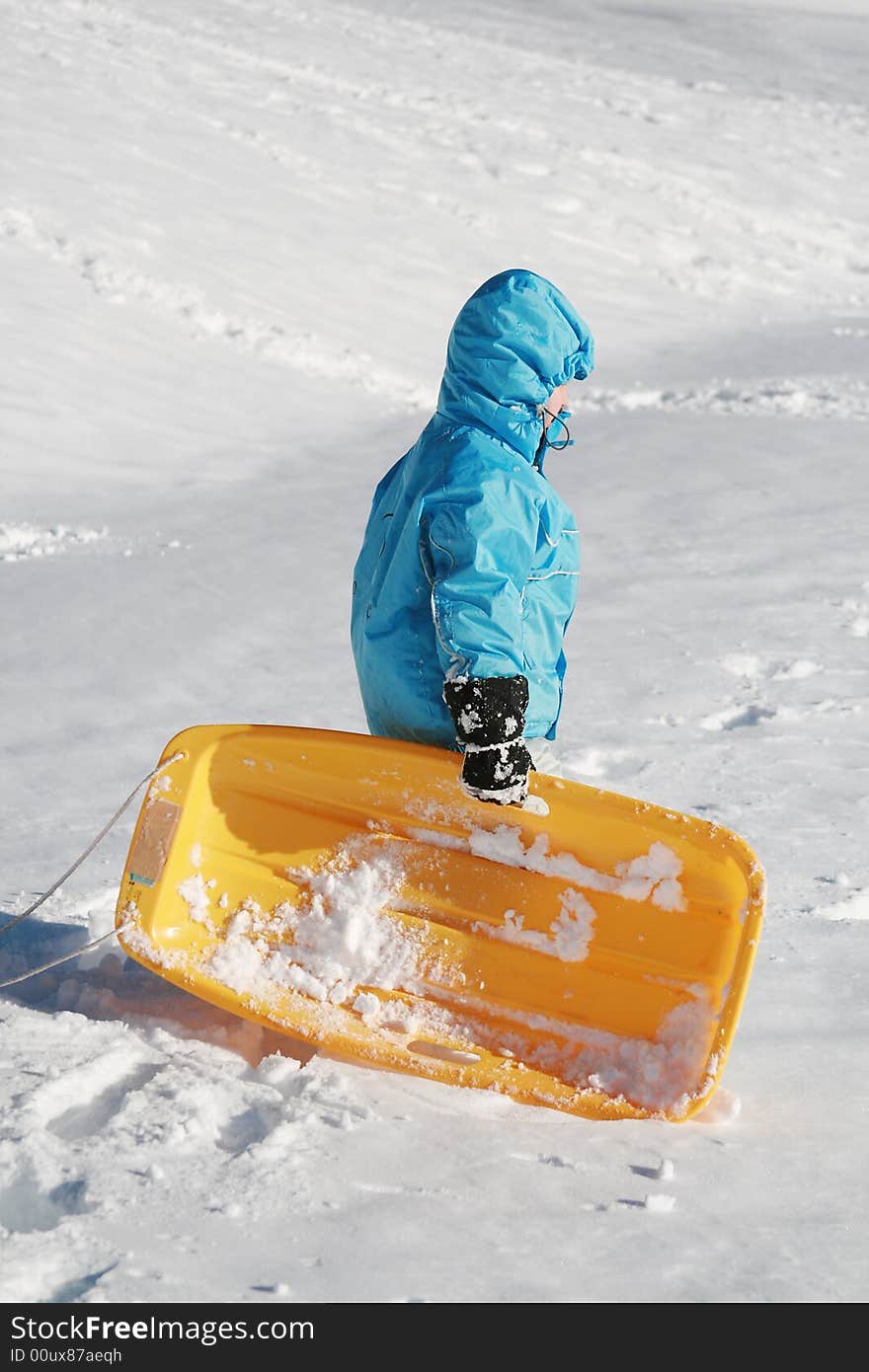 Boy going up to the snow hill with yellow plastic sled. Boy going up to the snow hill with yellow plastic sled