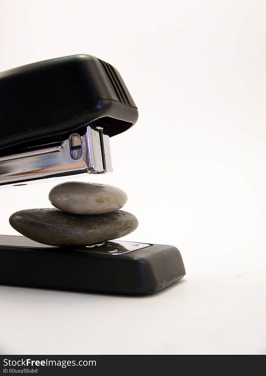 Close up image of a black stapler about to staple together two stones.  Vertical orientation. Close up image of a black stapler about to staple together two stones.  Vertical orientation.