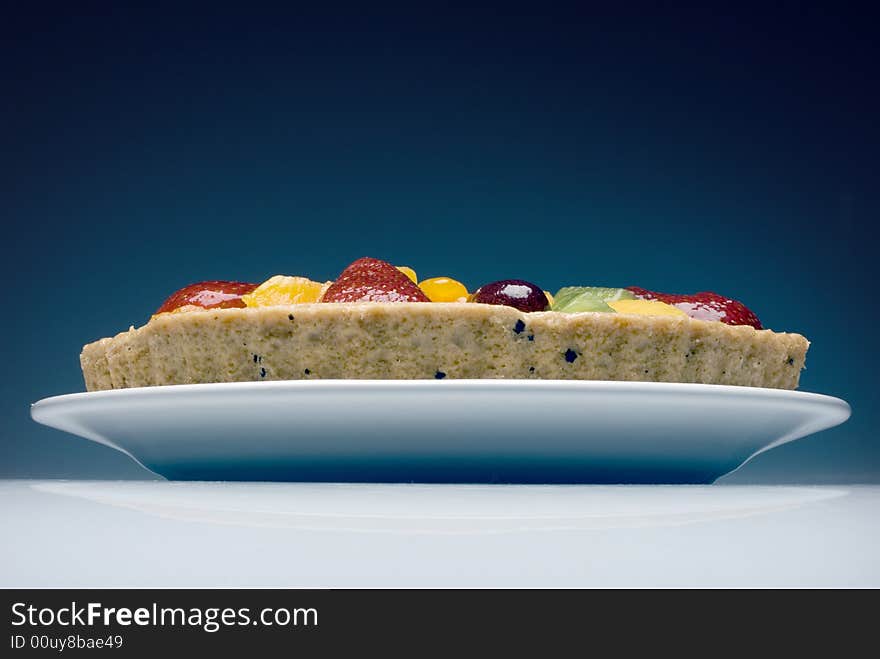 A fruit pie in a plastic transparent box on a gray to white background