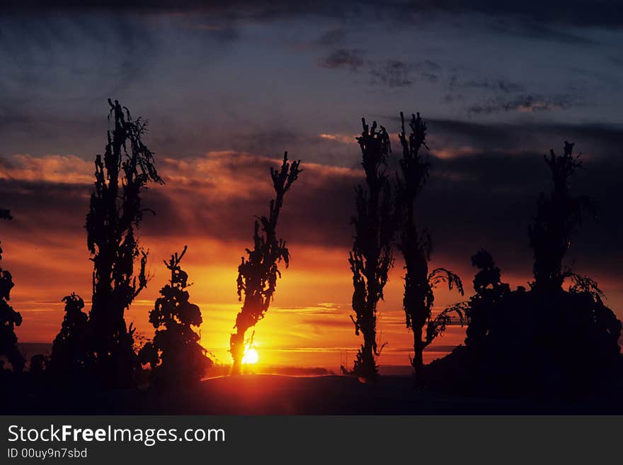 The sun sets through the clouded sky. The sun sets through the clouded sky