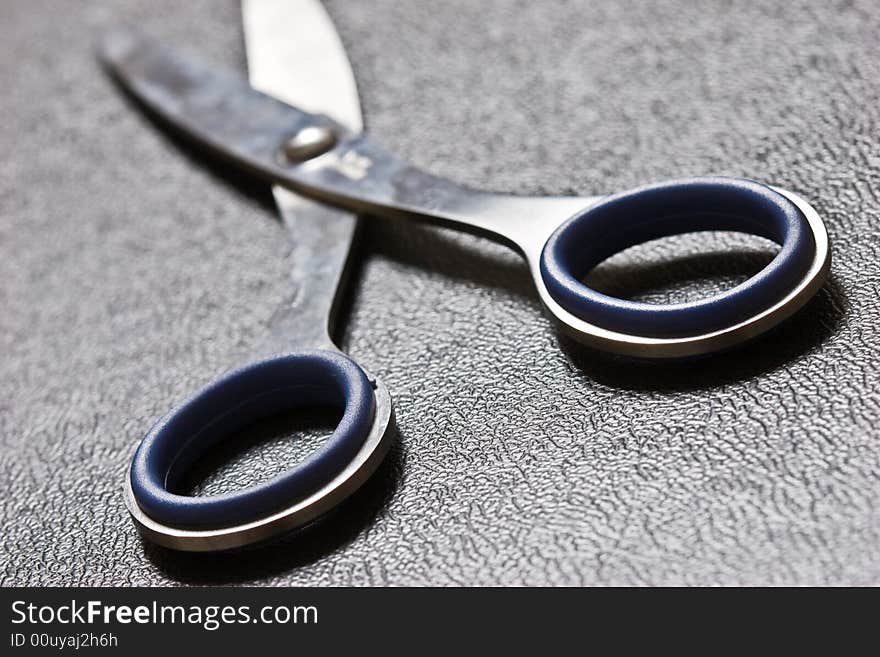 Photo of blue scissors on texture imitation leather