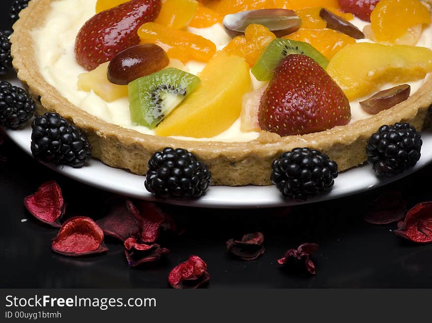 A fruit pie on a white plate on a black background